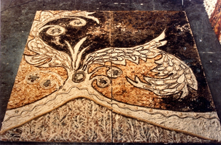 A photograph of a mural lying on the floor, with a tree-like design in different shades of brown.