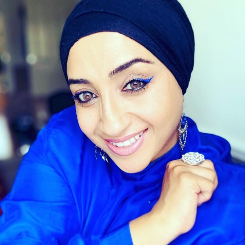 Head and shoulders photograph of Hafsah smiling wearing dark blue headscarf and bright blue top