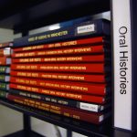 Stack of bound volumes on shelf with label 'oral histories'